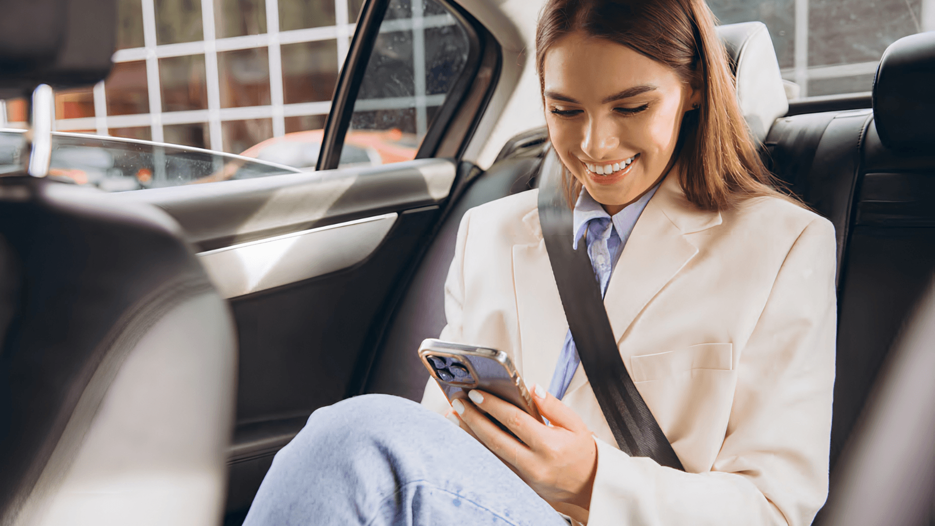 Pasajera sentada en la parte trasera de un auto usando MoviSur en su teléfono